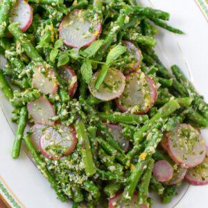 A close up of blanched asparagus salad with radishes and a gremolata sauce