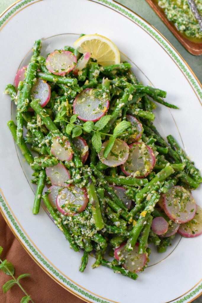Blanched asparagus salad with mint gremolata on a white serving platter with lemon zest on top