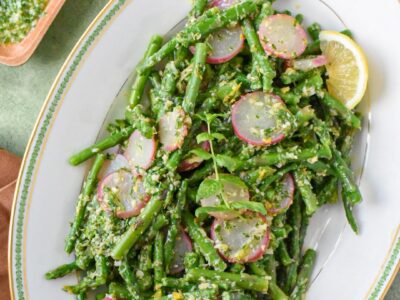 An overhead image of blanched asparagus salad with mint gremolata sauce on a white serving platter