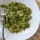 Fiddleheads in a white bowl with parmesan cheese and a fork