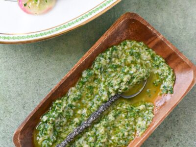 An herb gremolata sauce in a wooden serving dish with an old silver spoon