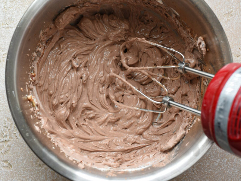 Chocolate greek yogurt mousse in a metal mixing bowl whisked with an electric mixer