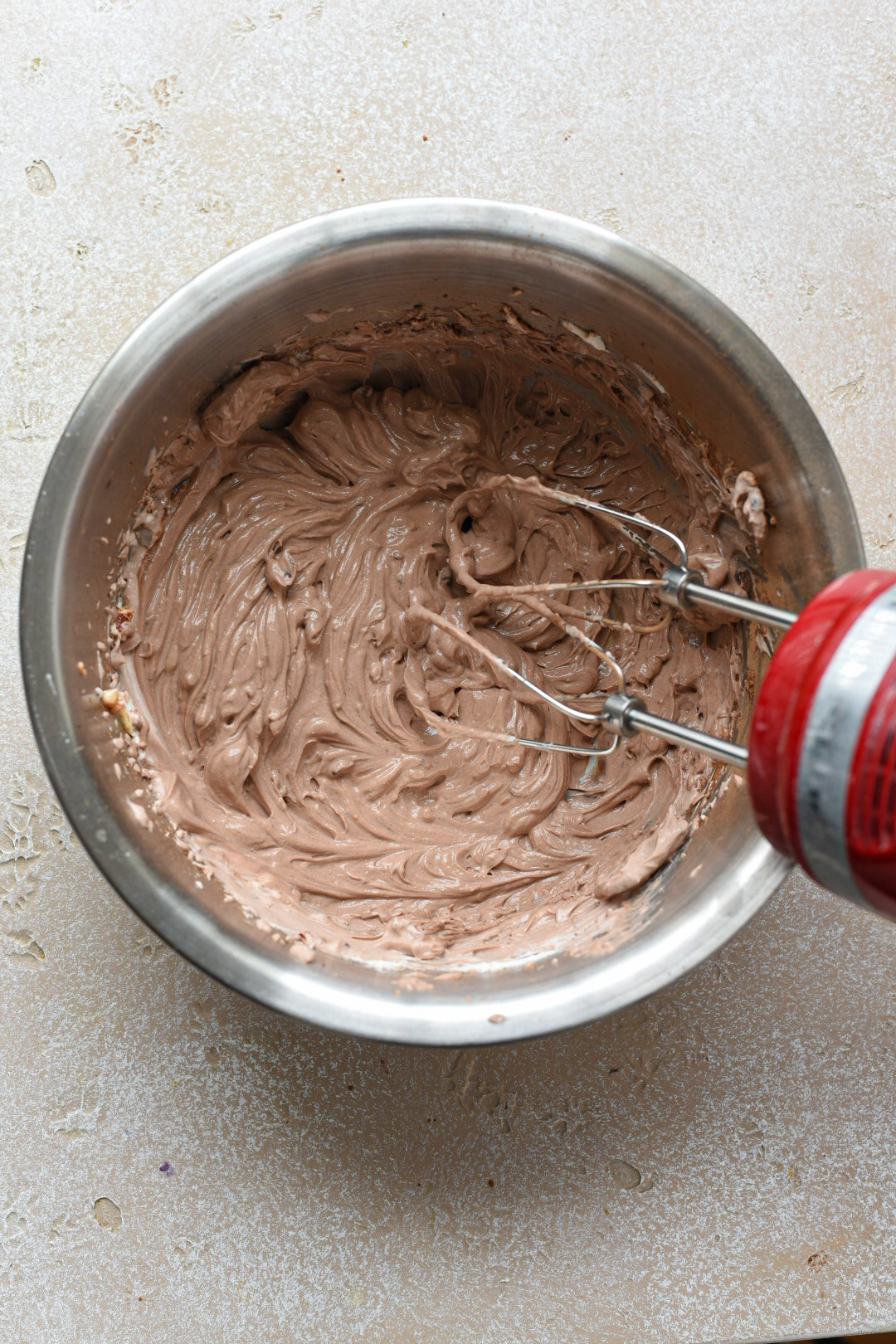 Chocolate greek yogurt mousse in a metal mixing bowl whisked with an electric mixer