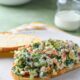 A mediterranean chopped sandwich on a white plate with homemade ranch dressing behind it