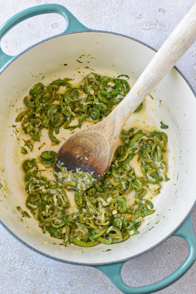 Sauteed fiddleheads in a dutch oven with garlic and parmesan