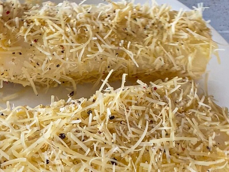 Shredded parmesan on two cod loins with black pepper on top