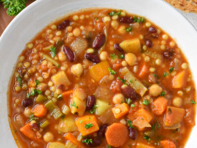 Sardinian minestrone soup in a white bowl with bread next to it.