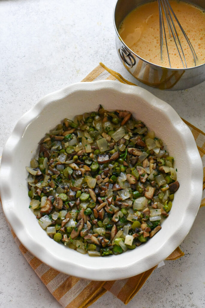 asparagus frittata recipe A pie dish filled with sauteed vegetables in a single layer