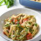 Boursin cheese pasta in a white bowl with cherry tomatoes, broccoli and basil on top.