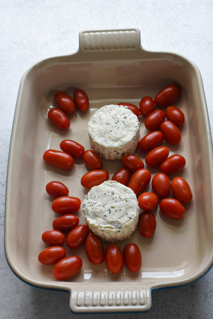 boursin cheese recipes Two wheels of boursin cheese in a baking dish surrounded by cherry tomatoes.