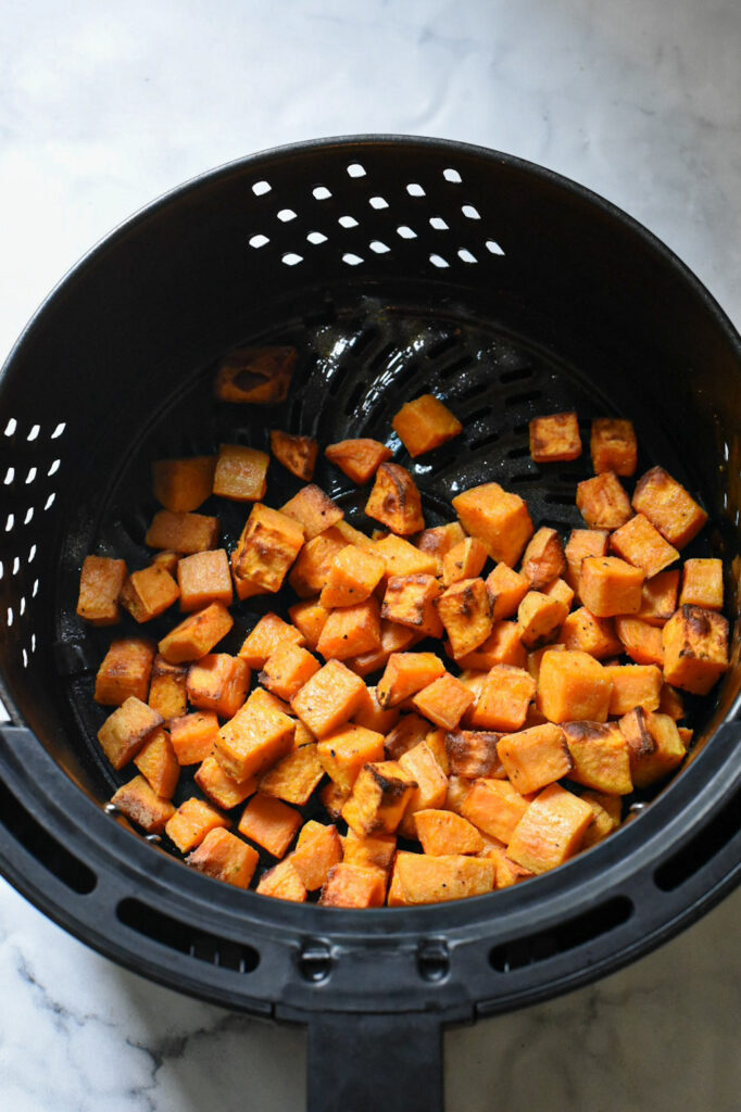 cubed sweet potato in air fryer Cooked cubed sweet potato in air fryer basket.