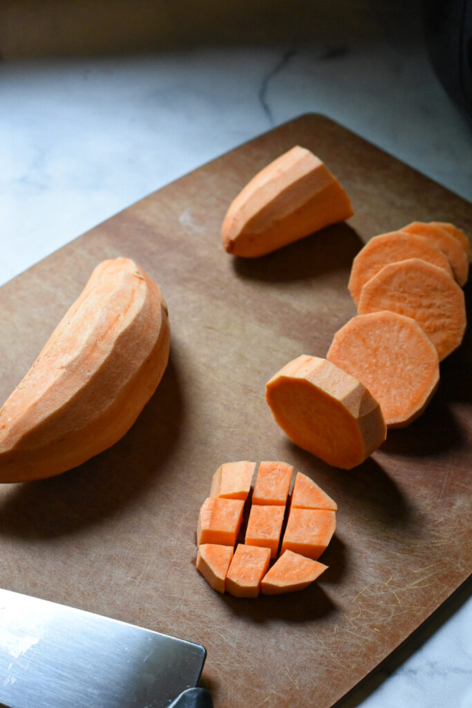 cubed sweet potato recipe Sweet potato medallion cut into cubes on a cutting board.