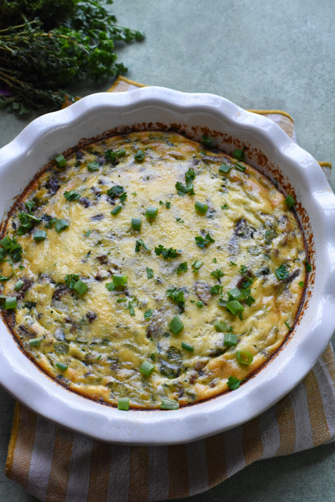 frittata with vegetables A baked vegetable frittata in a white pie dish sprinkled with fresh herbs.