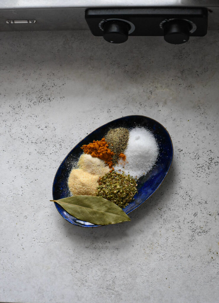 minestrone soup spices A small blue plate topped with a bunch of seasonings, salt and pepper, as well as a bay leaf.