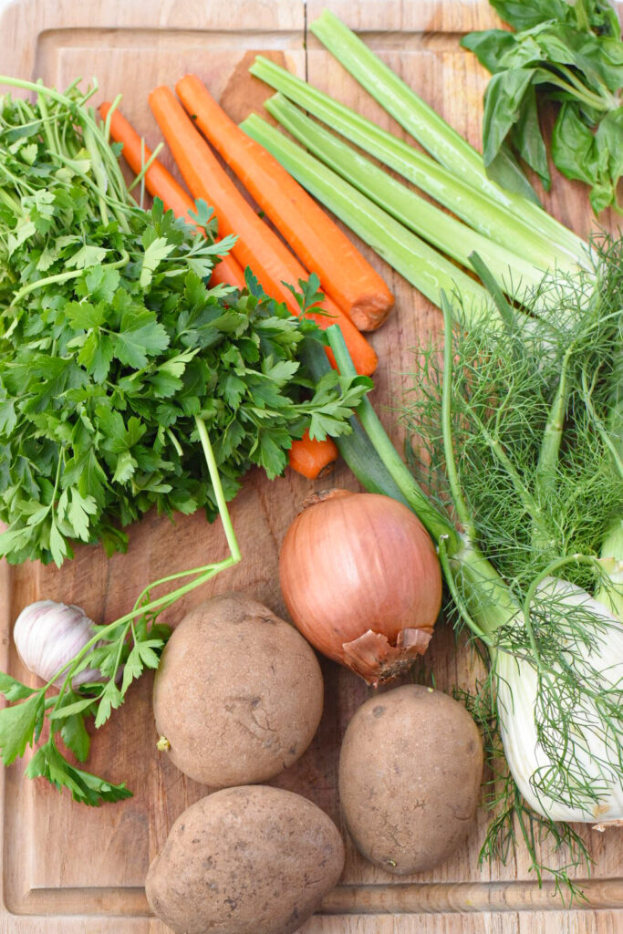 The vegetables used for sardinian minestrone soup on a wooden cutting board.
