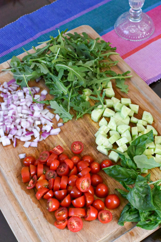 The ingredients to make orzo pasta salad lettuce wraps on a wooden cutting board.