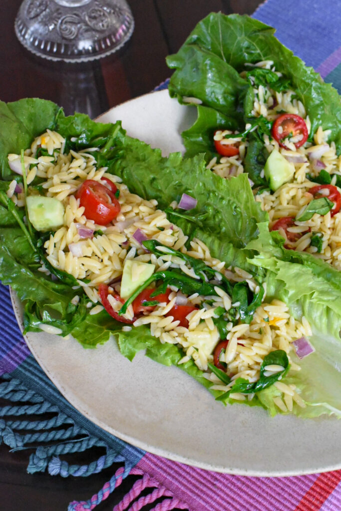 Two large lettuce wraps on a plate filled with an orzo pasta salad recipe.