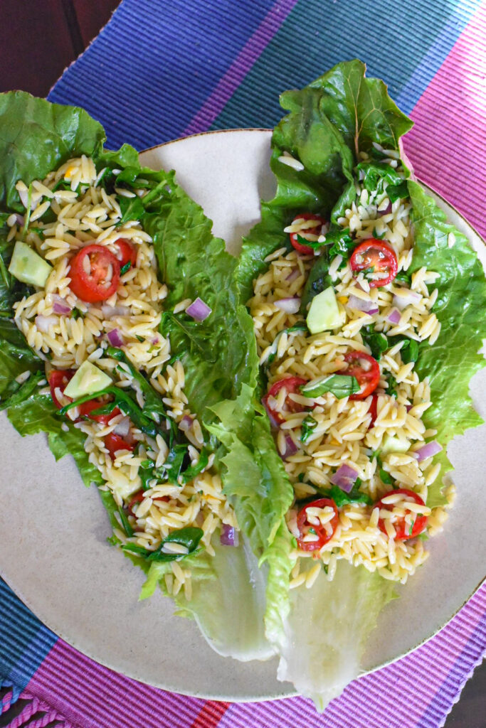 orzo pasta salad recipe Two romaine lettuce wraps filled with orzo pasta salad on a plate.