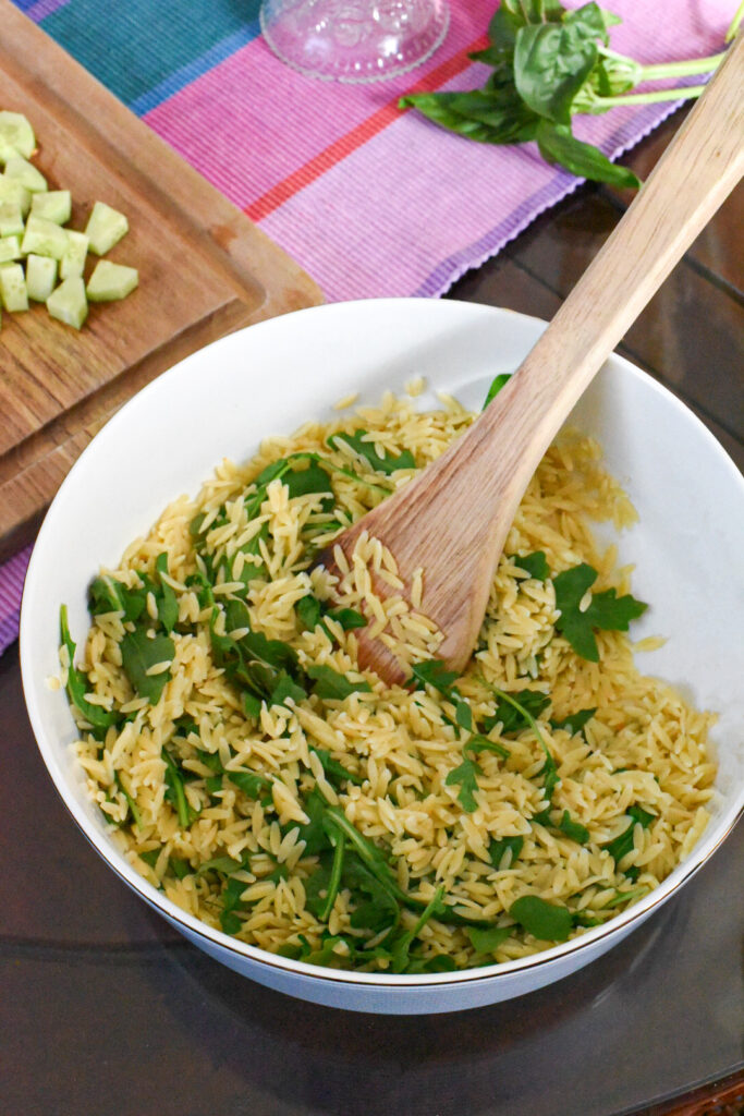 orzo salad A large serving bowl filled with pasta salad and arugula.