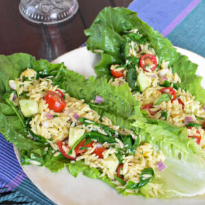 Orzo pasta salad lettuce wraps on a white plate.