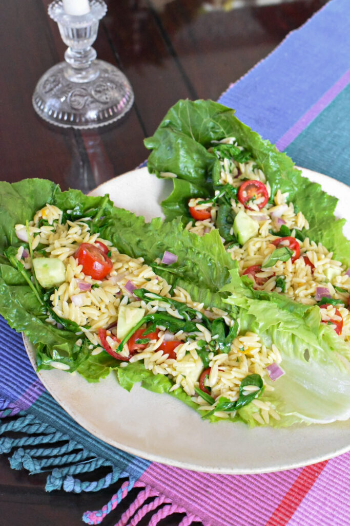 Orzo pasta salad served in two lettuce wraps on a plate.