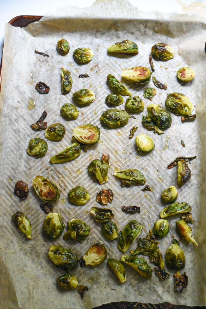 A baking sheet lined with parchment paper and filled with roasted brussels sprouts.