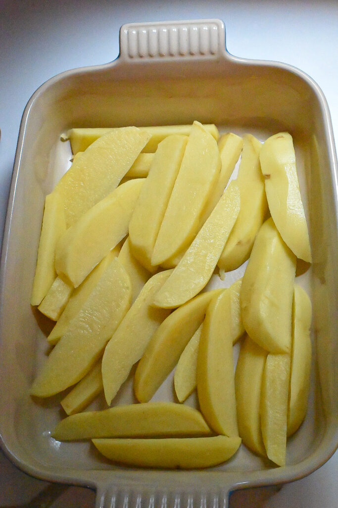 Wedged yukon gold potatoes in a baking dish.
