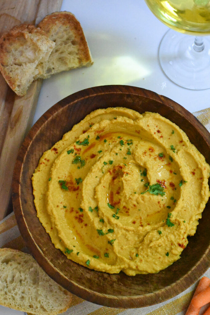 A pumpkin hummus recipe in a wooden bowl with toasted sourdough next to it.