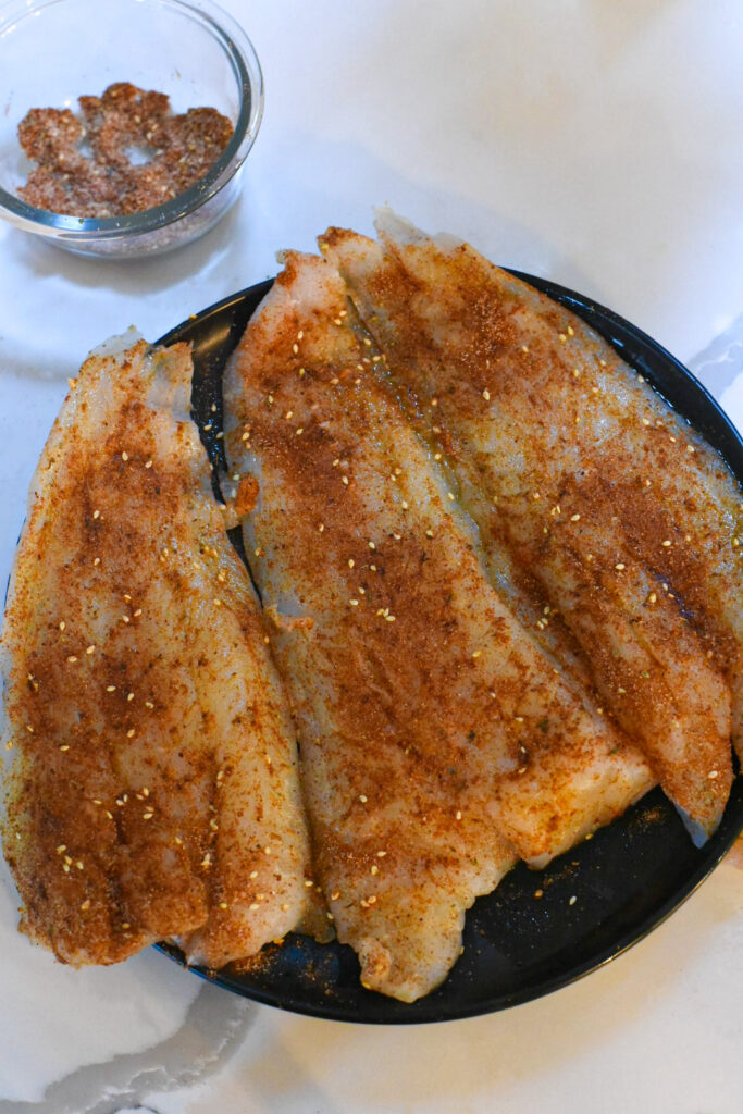 easy blackened cod recipe Raw cod on a plate covered in blackening seasoning.