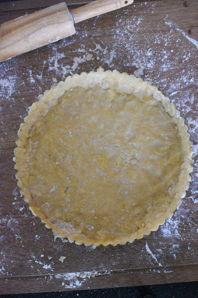 Raw tart dough pressed neatly into a tart pan.