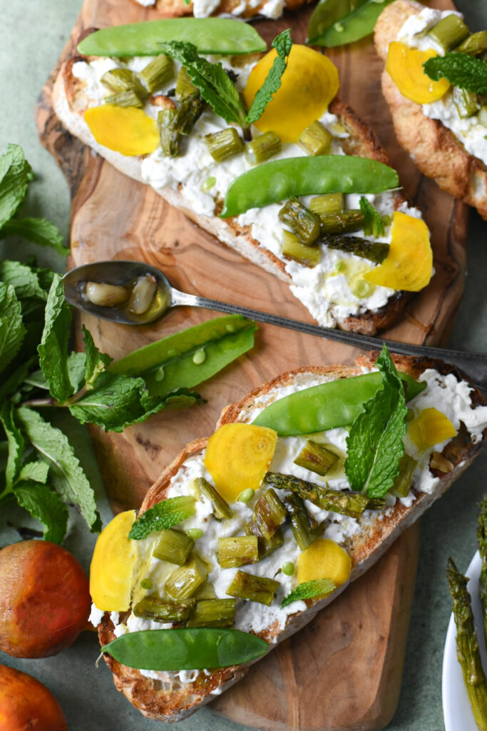 A few pieces of burrata toast with asparagus, snap peas and garlic confit.
